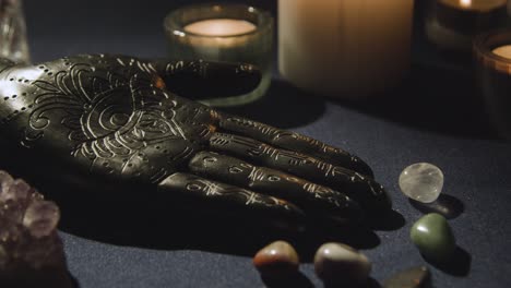 close up of model of hand used in palm reading surrounded by candles and crystals