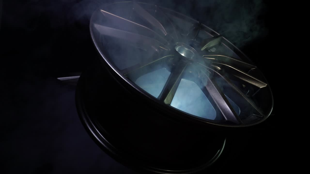 moderna hermosa rueda de aleación de automóviles en forma de rayos que es resaltado por rayos de luz y brillo, fondo negro