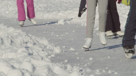 detail view to a ice skating track with people gracefully ice skating in group in harasov frozen lake in kokorin, czech republic - medium slow-motion static shot