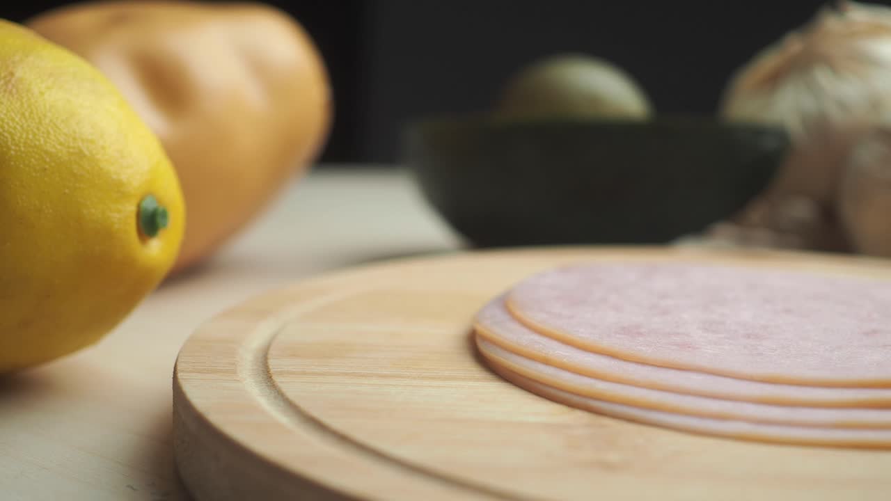 Ham slices, avocado, onions, and lemon on a cutting board