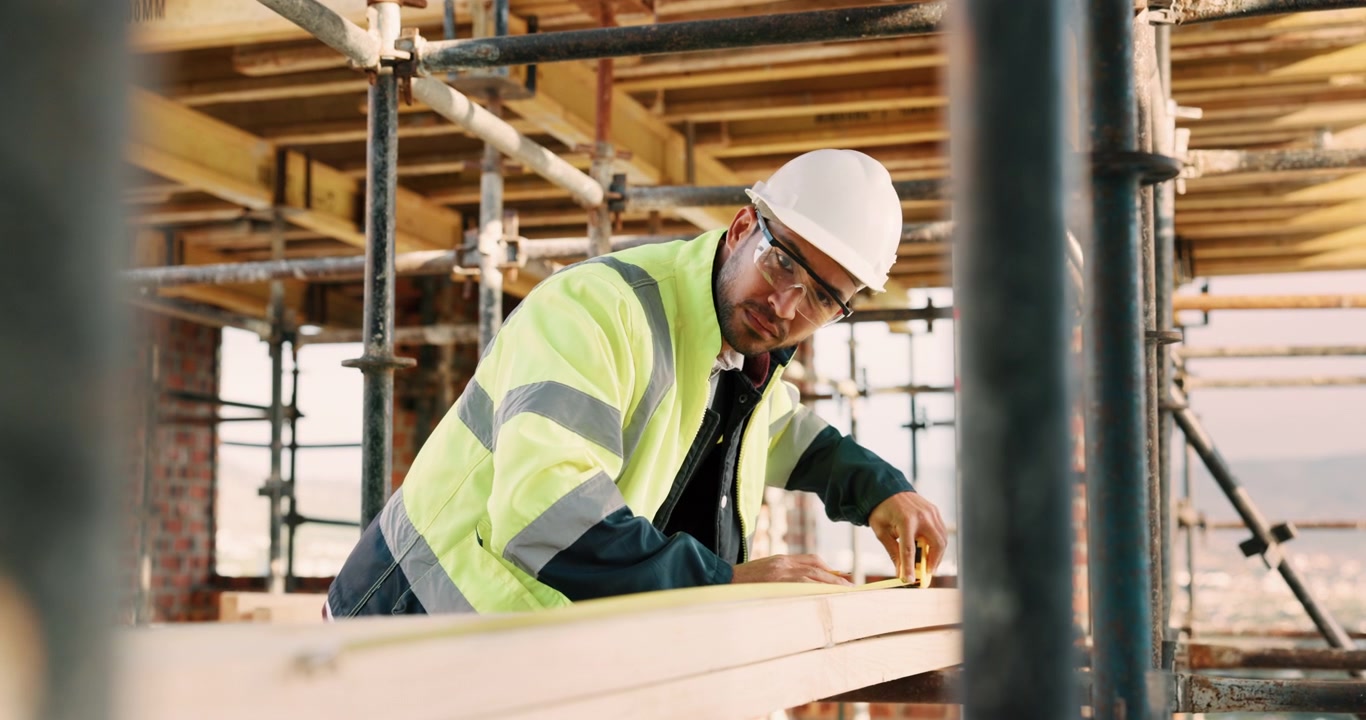 Construction Worker Measuring Wooden Beam on Building Site