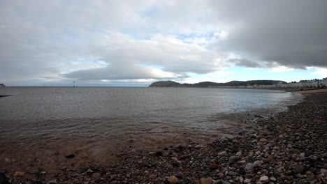 Time-lapse-stormy-overcast-waves-washing-over-seaside-pebble-beach-ocean-coastline