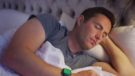 man lying in bed checking smart watch before going to sleep