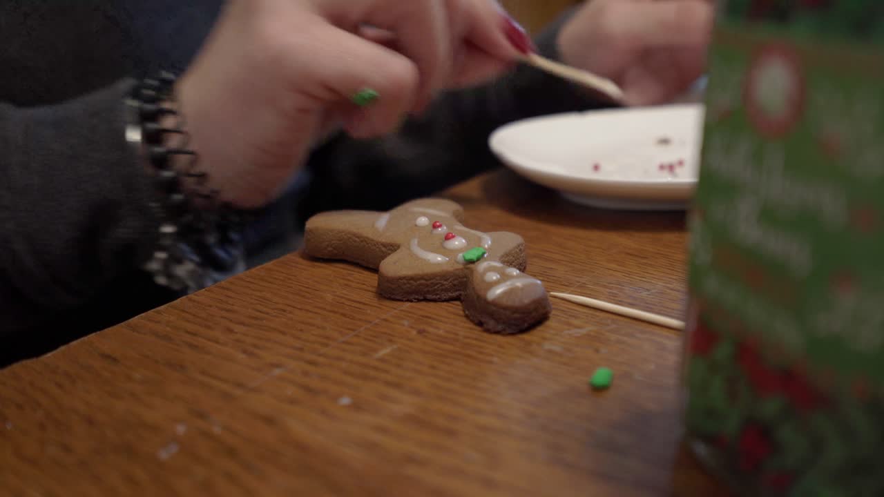 Close-up shot of a lady putting icing on a gingerbread man