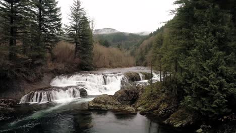 Cinematic-aerial-starts-at-road-and-flies-towards-roaring-waterfall