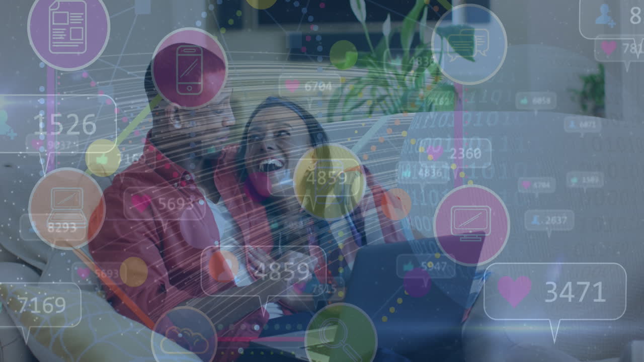 animación de iconos de las redes sociales sobre una pareja afroamericana sonriendo mientras usan una computadora portátil en casa.