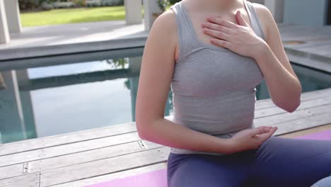 Sección-Media-De-Una-Mujer-Caucásica-Enfocada-Practicando-Yoga-En-Un-Jardín-Soleado,-Cámara-Lenta