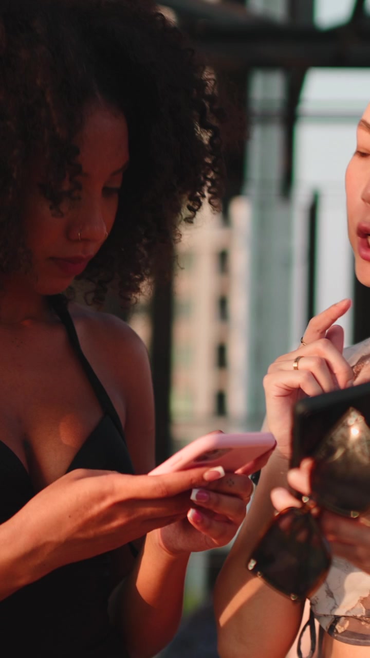 Duas Mulheres Diversas Discutindo Conteúdo em Smartphones em um Lounge de Cobertura ao Ar Livre