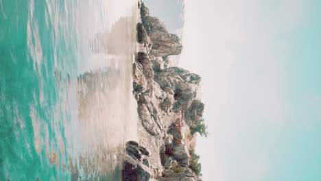 vertical video of large rock island in the middle of the sea water