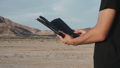 man watching a black book in the desert