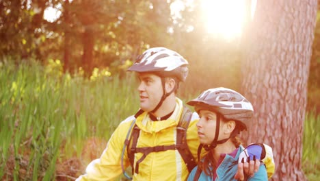 mountain biking couple walking on forest trail with bike