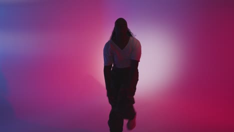 studio shot of young woman dancer dancing against blue and pink lit background 12