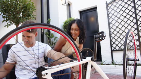 repairing bicycle, young multiracial couple sitting outside house, enjoying time together