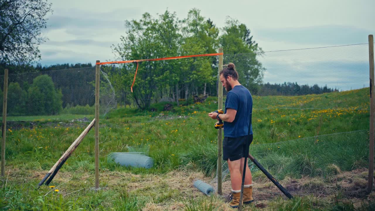 Man Constructing Fence With Fence Wire - Wide Shot