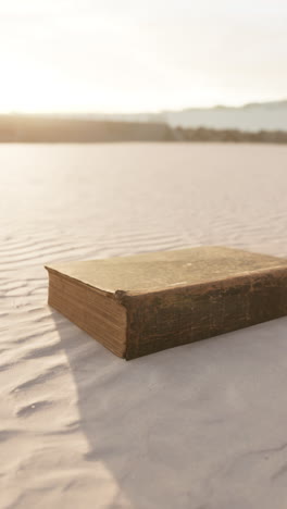 old book on a sandy beach at sunset