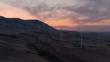 Beautiful-Aerial-Landscape-View-of-Wind-Turbines-on-a-Windy-Hill-during-a-colorful-sunrise