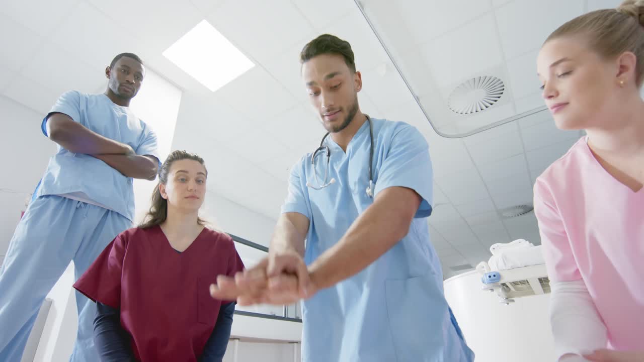 Medico di etnia mista che addestra medici tirocinanti nella procedura di rianimazione cardiopolmonare d'emergenza usando un manichino, al rallentatore.
