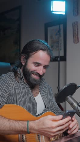 man playing acoustic guitar and using smartphone