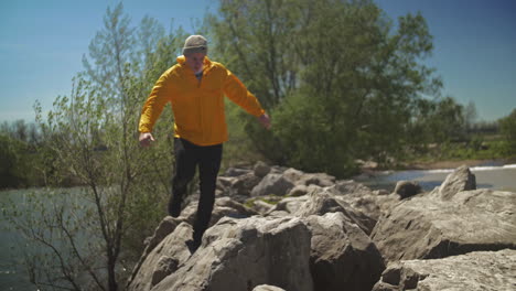 hombre caucásico caminando por las grandes rocas junto a un lago