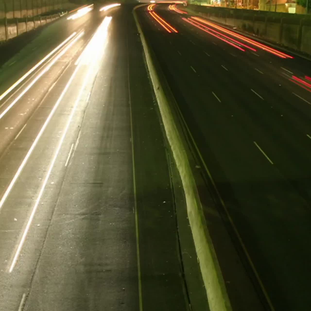 una inclinación lenta hacia arriba revela que el tráfico se mueve a la velocidad de la luz a lo largo de una autopista en esta toma de lapso de tiempo
