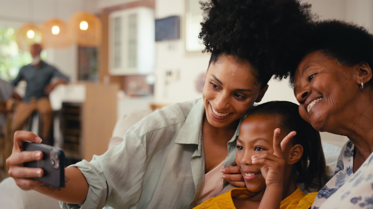 familia de mujeres de varias generaciones posando para una selfie en el teléfono móvil sentadas en el sofá en casa juntas