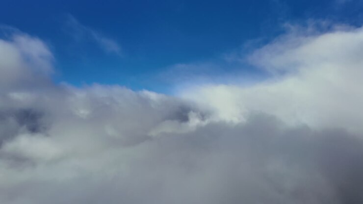Immersive pilot’s view while flying in a dreamlike cloudscape full of ethereal clouds under a blue sky. Ultra-realistic 4K shot