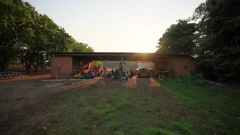 exterior view of a rural shed at sunset, surrounded by greenery, creating a peaceful countryside scene