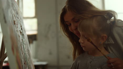 smiling art teacher holding girl hand in workshop