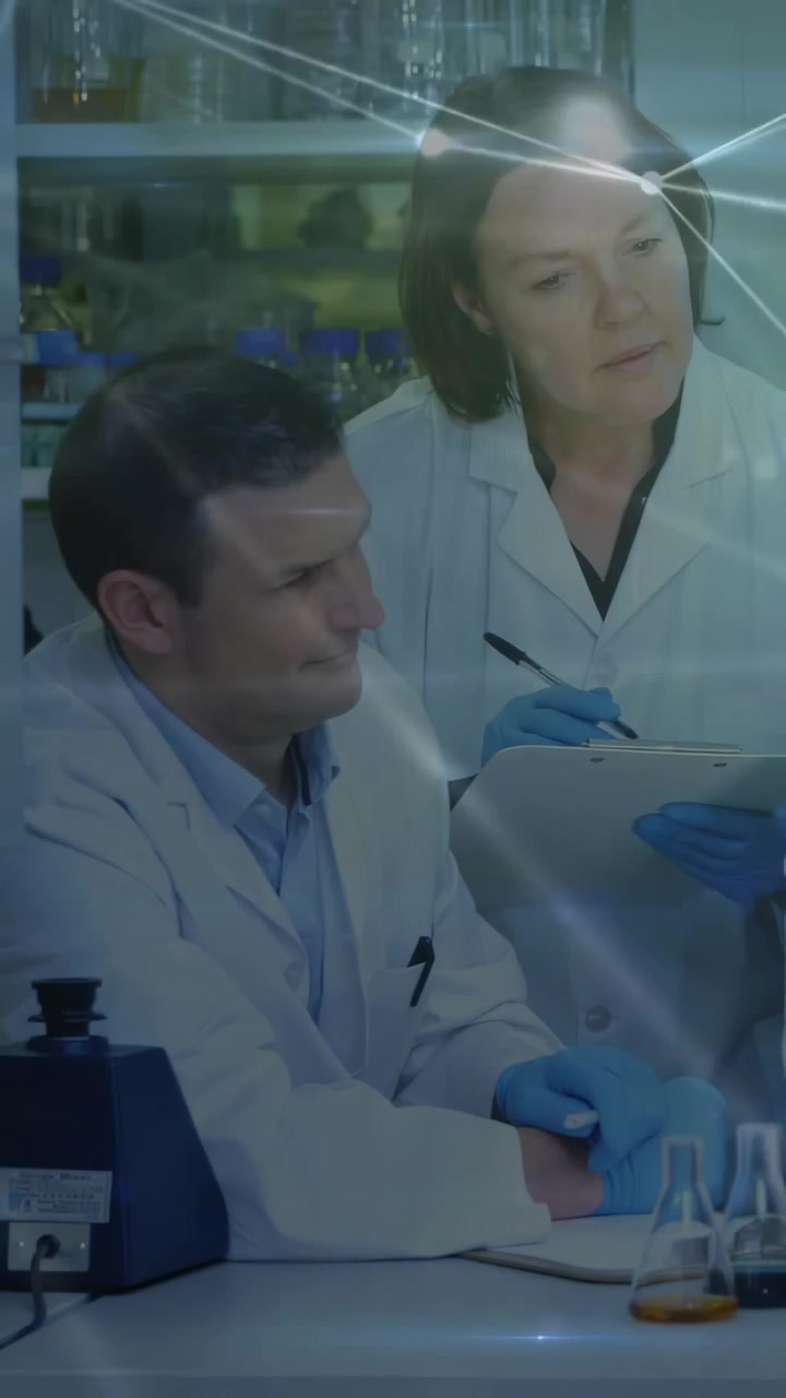 Video vertical: Dos investigadores inclinan una tableta, señalando y revisando datos de laboratorio en medio de destellos de red.