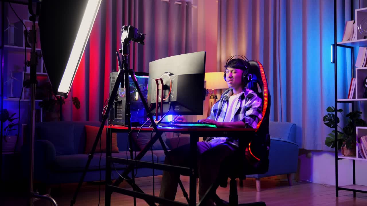 아시안 소년 스트리머는 개인 컴퓨터에서 네트워크를 통해 게임을하는 동안 스트레칭합니다. 라이브 스트리밍 비디오 게임, rgb led 스트립 라이트에 의해 조명 된 책상