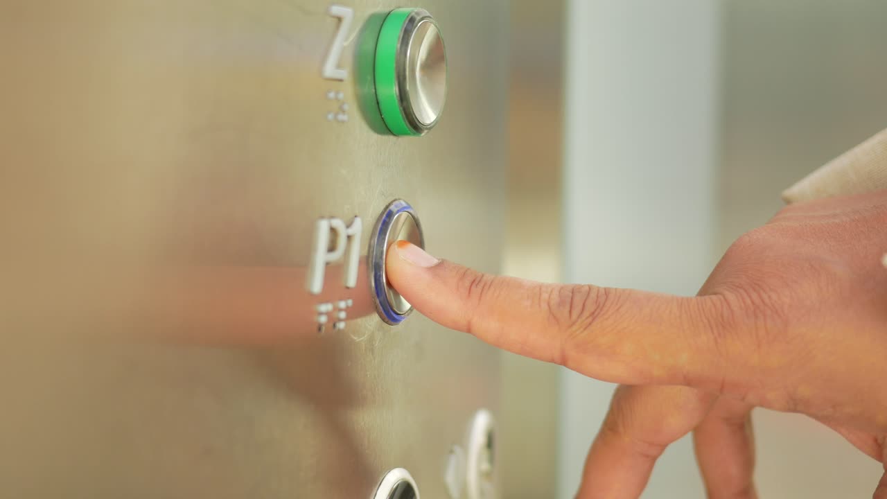 una persona presionando el botón para el primer piso en un ascensor