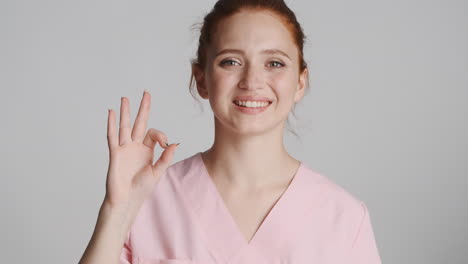 redheaded doctor in front of camera on gray background.