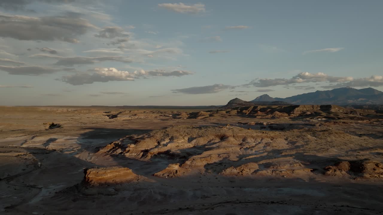 Pôr do sol no deserto projeta sombras sobre a paisagem árida - revelação aérea descendente