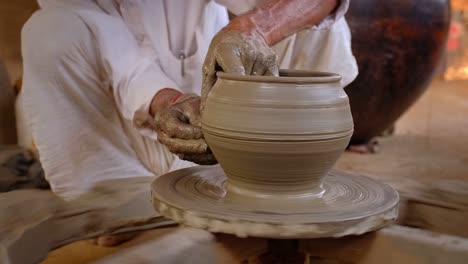 skilled hands of potter shaping the clay on potter wheel and sculpting clay pot jar. shilpagram, udaipur, rajasthan, india