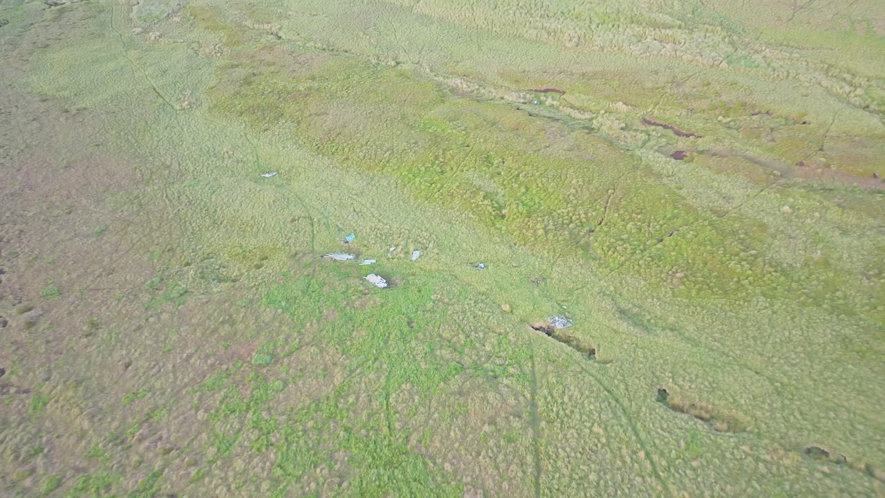 Aerial over green hills to Sabre F.Mk 4 fighter jet wreck site from Cold War in Peak District National Park, UK