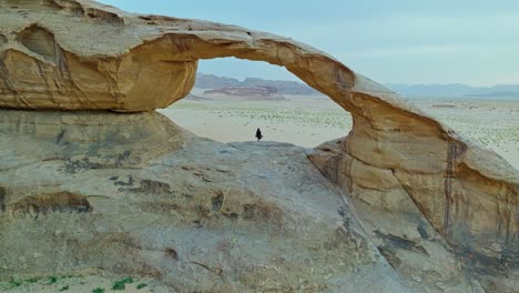 silueta de una mujer bajo el puente de burdah rock en el área protegida de wadi rum, jordania, oriente medio