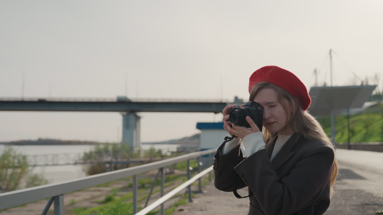 Donna felice che fotografa. Donna che cattura momenti lungo il fiume. Donna allegra che scatta foto in una scena urbana in riva all'acqua. Donna vivace con la macchina fotografica su un ponte lungo il fiume che cattura immagini gioiose e spontanee.