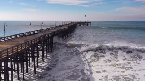 aerial over huge waves rolling in over a california pier in ventura california during a big winter storm suggests global warming and sea level rise or tsunami 4