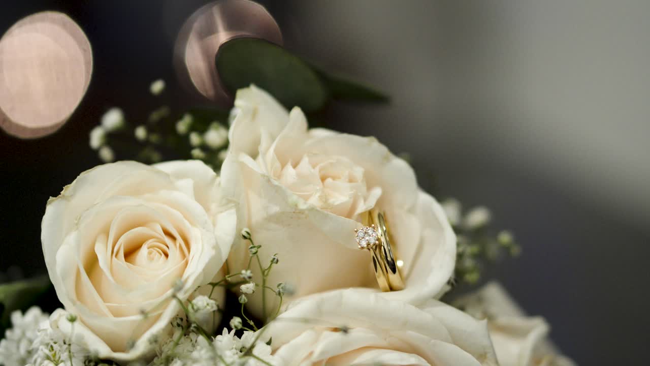 Bouquet of white roses with shiny wedding rings between their petals