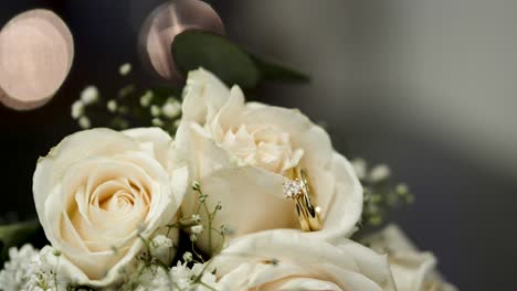 Bouquet-of-white-roses-with-shiny-wedding-rings-between-their-petals