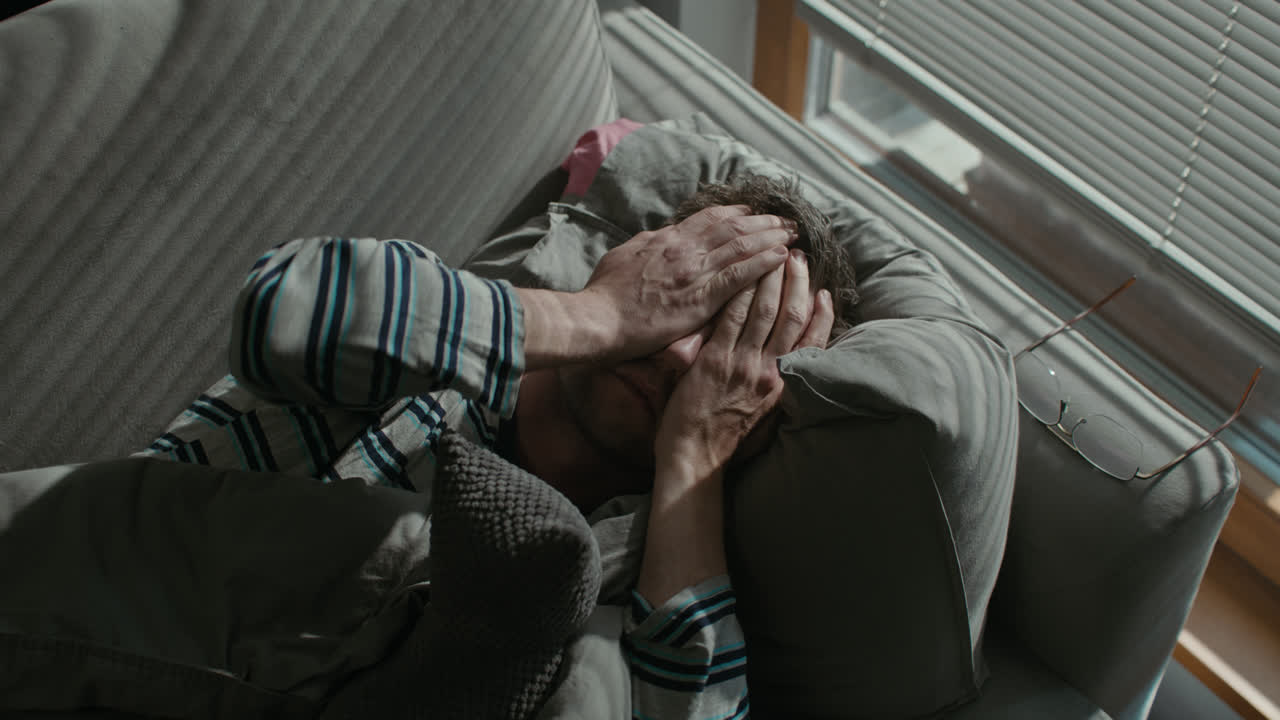 A sad man wakes up tired on his sofa
