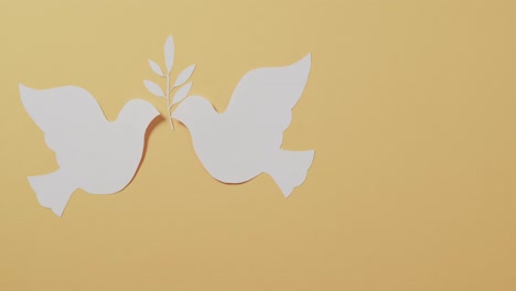 close up of white doves with leaf and copy space on yellow background