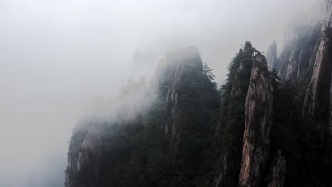 china steep granite mountain peaks, clouds passing over summit aerial view, background