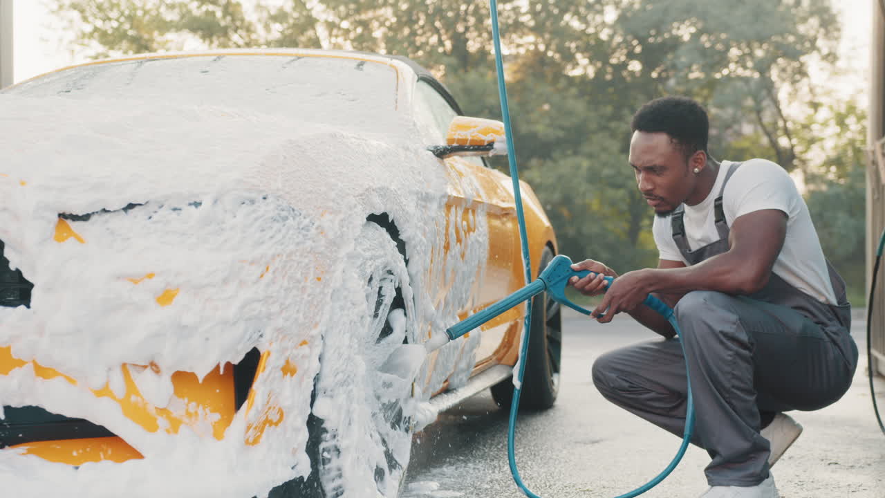 사람이 거품으로 노란색 컨버터블 자동차를 고 있습니다.