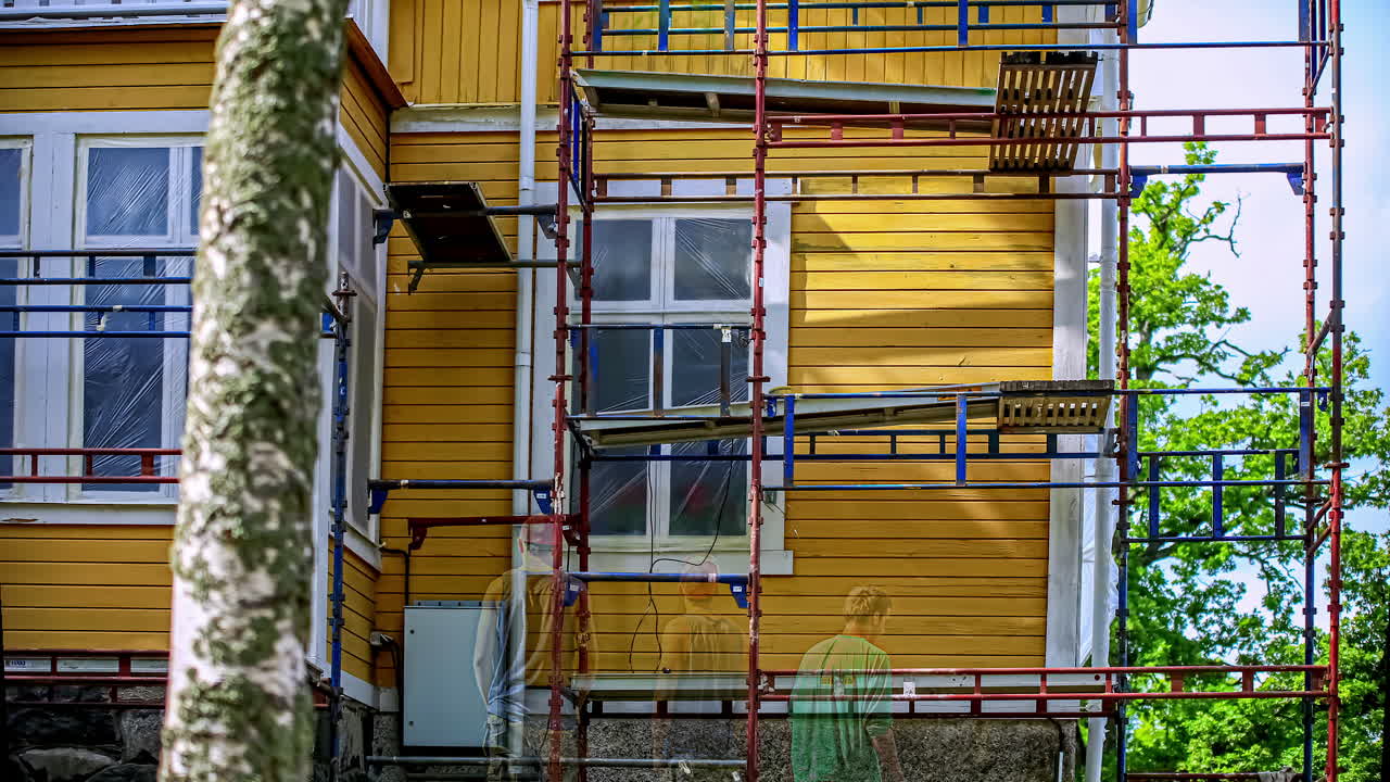 captura de tiempo de un trabajador que repara el exterior de una casa de madera sin terminar en un día soleado