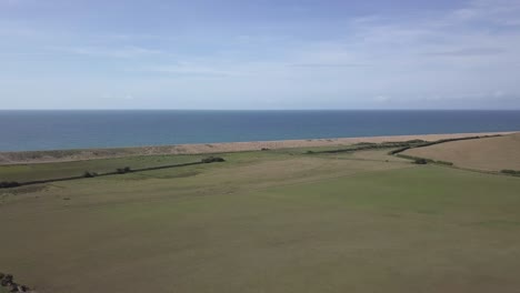 aerial tracking forward over a vast field on the coat next to chesil beach