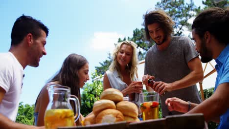 grupo de amigos interactuando entre sí mientras comen en una fiesta de barbacoa al aire libre