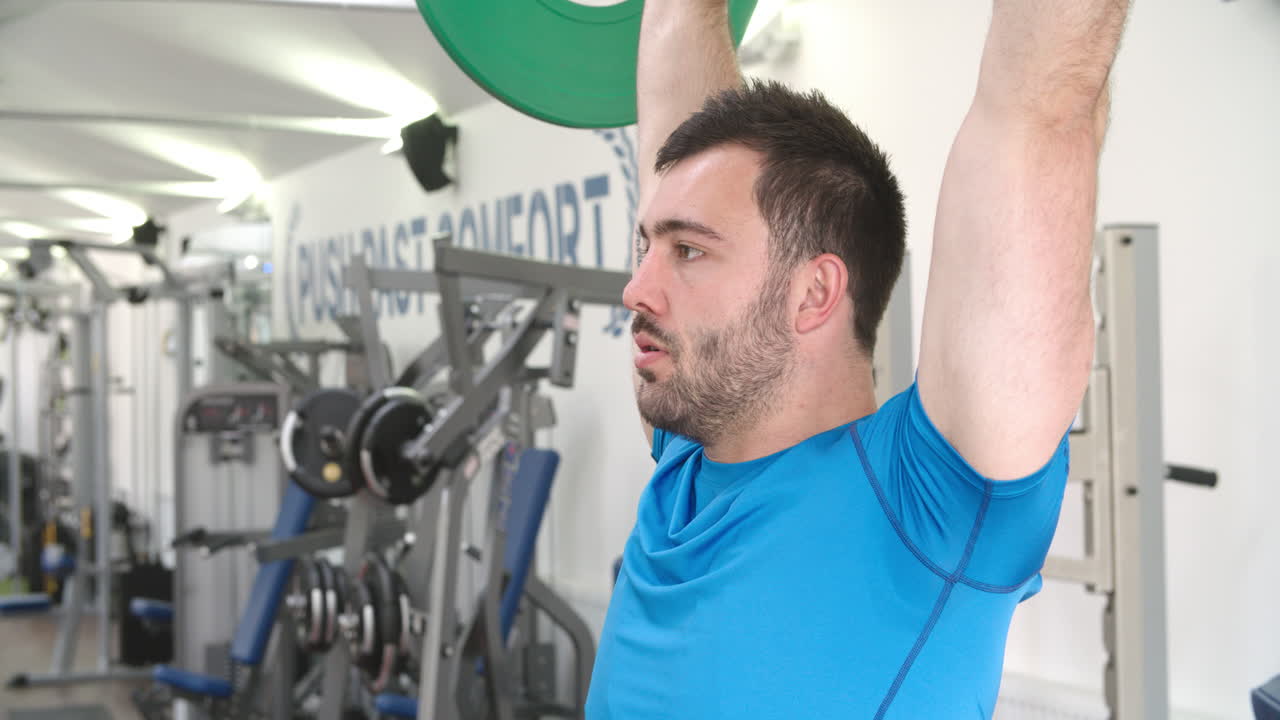 joven presionando barras en el hombro en un gimnasio