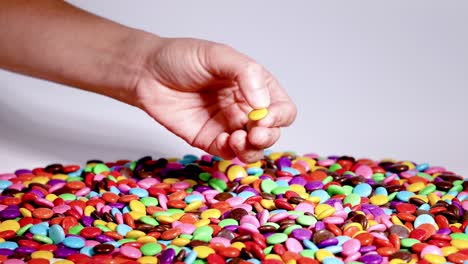 hand picking candies from a colorful pile