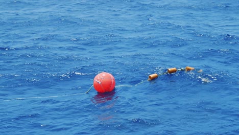 orange buoy floating past outrigger boat in caribbean sea